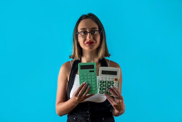 Portret van een aantrekkelijk bang nerveus meisje met een rekenmachine die nagels bijt, geïsoleerd over een blauwe pastelkleurige achtergrond, een zakelijke kantoorvrouw, een bange vrouw