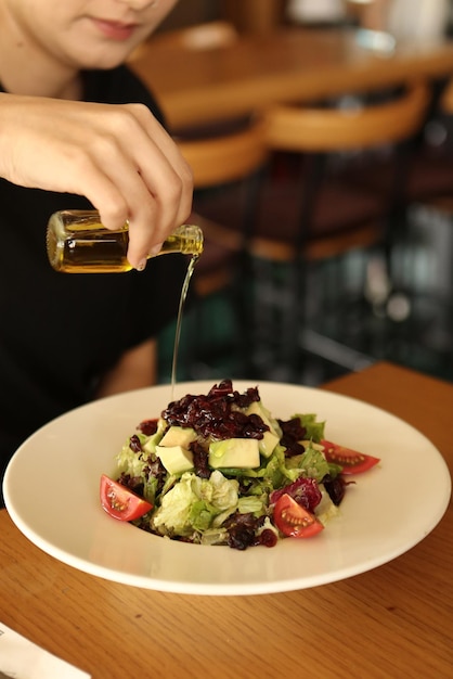 Portret van een aantrekkelijke blanke lachende vrouw die salade eet, focus op hand en vork