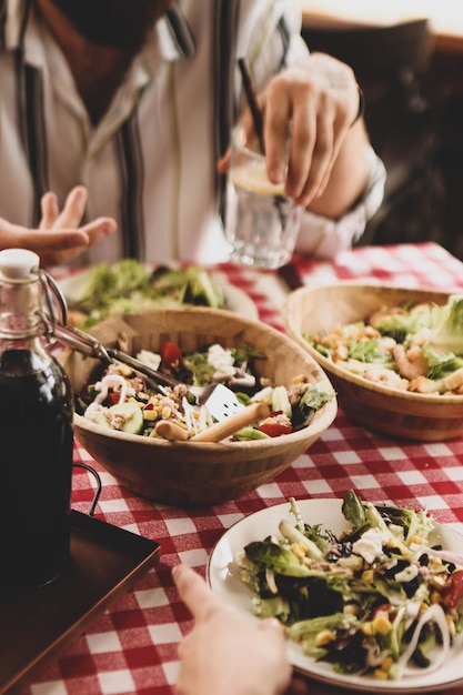 Portret van een aantrekkelijke blanke lachende vrouw die salade eet, focus op hand en vork