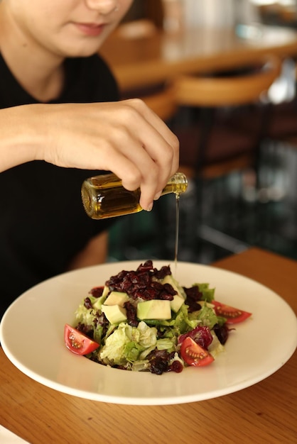 Portret van een aantrekkelijke blanke lachende vrouw die salade eet, focus op hand en vork