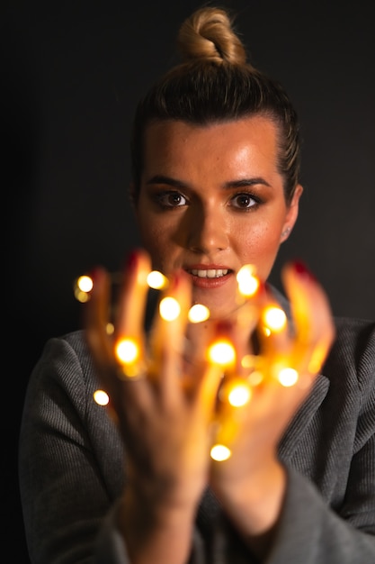 Portret van een aantrekkelijke blanke vrouw met lichtslingers om haar hand gewikkeld