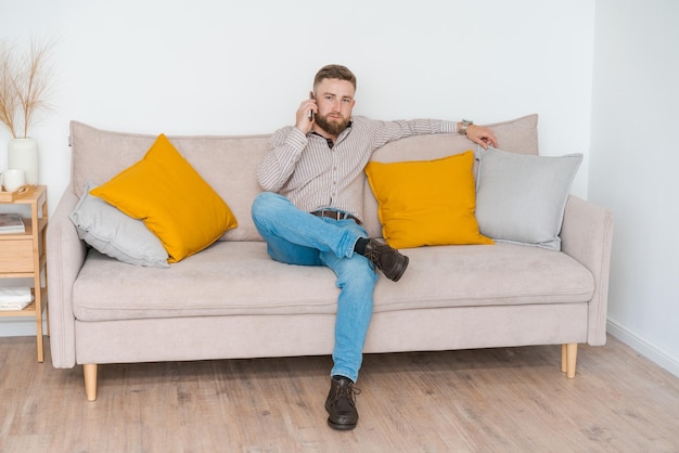 Portret van een aantrekkelijke glimlachende jonge bebaarde man gekleed in vrijetijdskleding