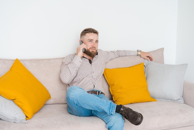 Portret van een aantrekkelijke glimlachende jonge bebaarde man gekleed in vrijetijdskleding