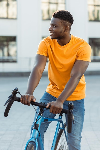 Portret van een aantrekkelijke jonge Afrikaanse man die op een stadsstraat fietsen