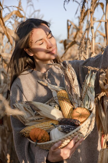 Portret van een aantrekkelijke jonge vrouw in een herfstgraanveld tussen droge bladeren met een oogst in haar handen.