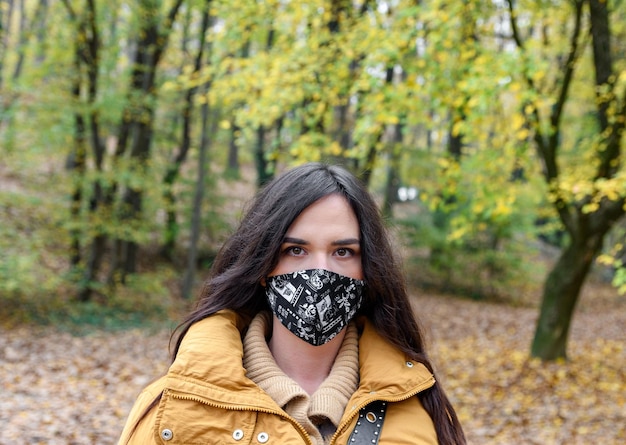 Portret van een aantrekkelijke jonge vrouw met een geel jasje en een zwart beschermend gezichtsmasker