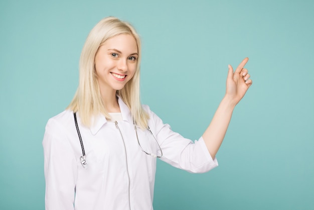 Portret van een aantrekkelijke jonge vrouwelijke arts in witte jas op blauwe achtergrond