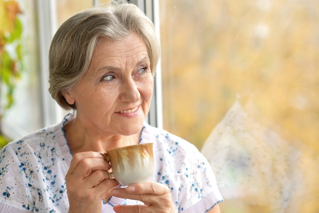Portret van een aantrekkelijke oudere vrouw met koffiekopje