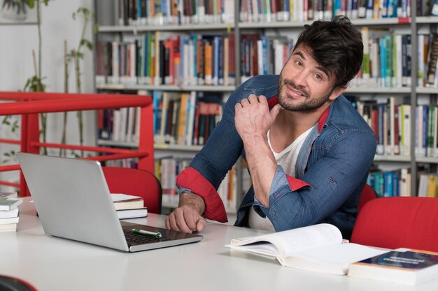 Portret van een aantrekkelijke student die wat schoolwerk doet met een laptop in de bibliotheek