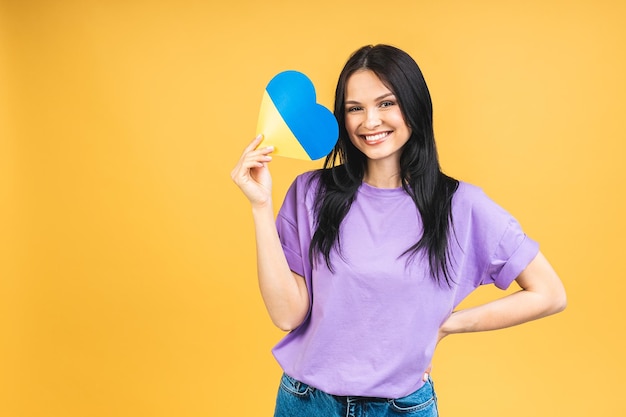 Portret van een aardige, mooie, vrolijke vrouw die de oekraïense vlag in handen houdt en plezier heeft geïsoleerd over een gele pastelkleurige achtergrond