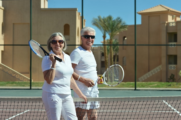 Portret van een actief hoger paar op tennisbaan