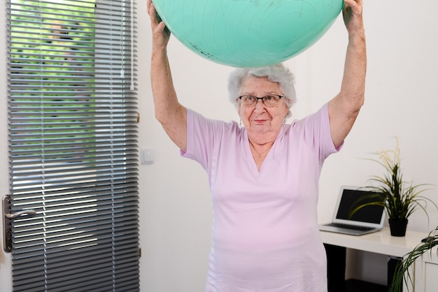 Portret van een actieve en dynamische senior vrouw die thuis sportfitness doet