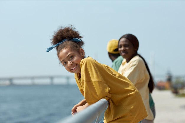 Portret van een Afrikaans-Amerikaans meisje dat naar de camera glimlacht terwijl ze met haar ouders op de pier staat