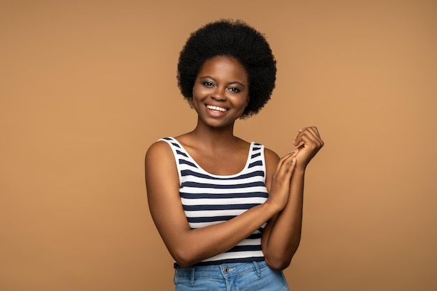 Foto portret van een afrikaans-amerikaanse vrouw die wijd glimlacht en poseert voor een opname en naar de camera kijkt met een gelukkig gezicht