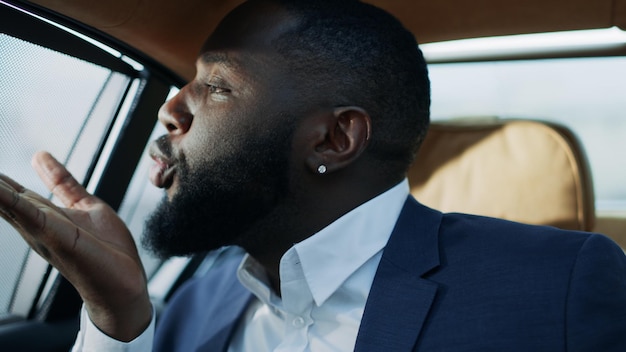 Portret van een Afrikaanse man die een kus blaast op de achterbank van de auto Zakenman flirten