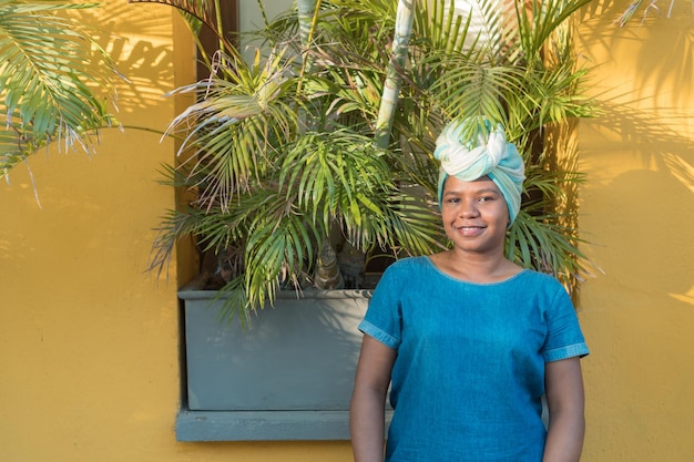 Portret van een Afrikaanse vrouw met een kleurrijke traditionele hoofdbedekking in de open lucht.