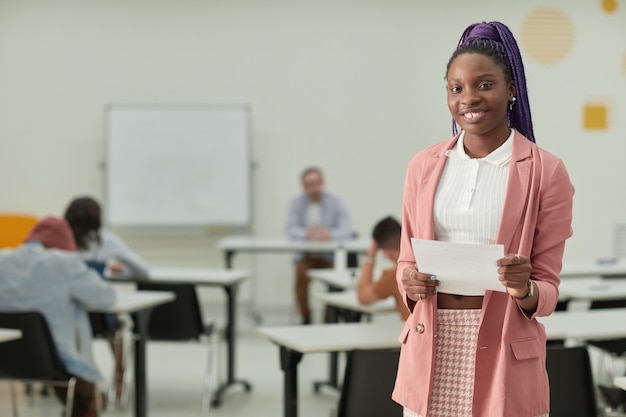 Portret van een Afro-Amerikaans tienermeisje in het klaslokaal dat vrolijk glimlacht naar de camera en een testcertificaat vasthoudt, kopieer ruimte