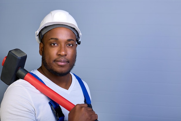 Portret van een Afro-Amerikaanse arbeider in overall op een grijze achtergrond