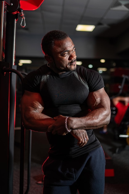 Portret van een Afro-Amerikaanse fitnesstrainer kijkt naar de zijkant op de achtergrond van moderne sportuitrusting Gezond levensstijlconcept