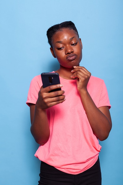 Portret van een afro-amerikaanse jonge vrouw die chat met een vriend die smartphone gebruikt