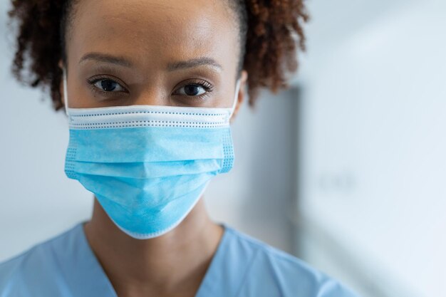 Portret van een Afro-Amerikaanse vrouwelijke arts met een masker in de ziekenhuisgang