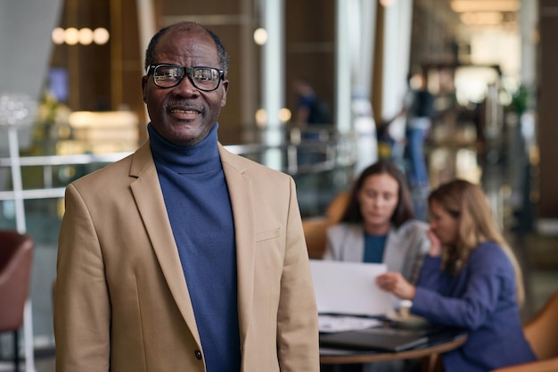 Portret van een Afro-Amerikaanse zakenman die naar de camera glimlacht terwijl hij zijn collega's ontmoet