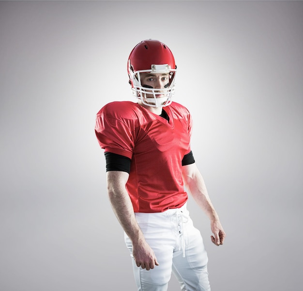 Foto portret van een amerikaanse voetbalspeler die zijn helm draagt tegen een grijze achtergrond