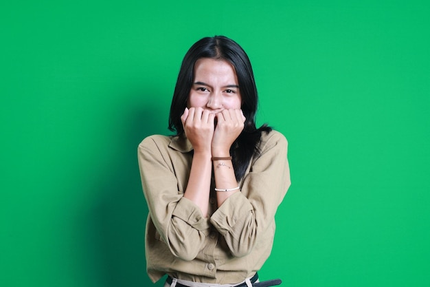 Portret van een angstige jonge vrouw die nagels bijt op een groene achtergrond