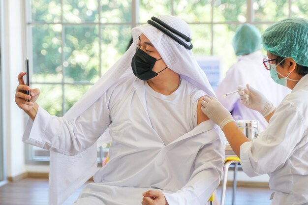 Portret van een Arabische moslimman selfie per telefoon op na het krijgen van een covid-vaccin om immuniteit te krijgen