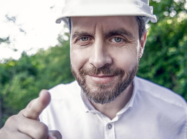 Portret van een arbeider met een veiligheidshelm die naar buiten wijst