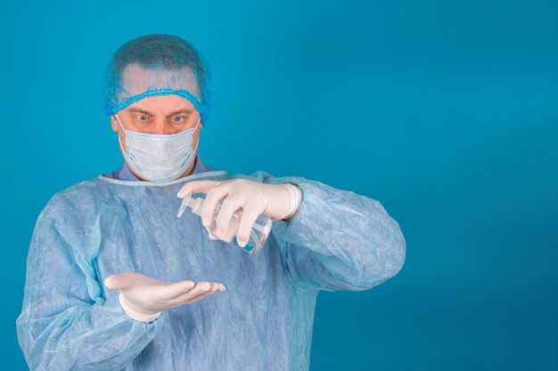 Portret van een arts of chirurg met een beschermend kapmasker en handschoenen op een blauwe achtergrond
