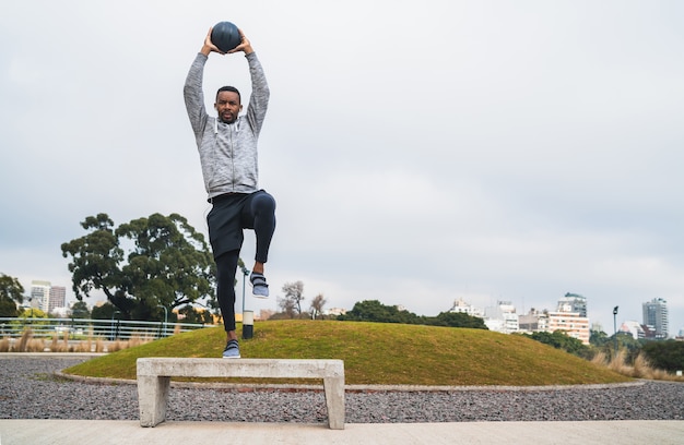 Portret van een atletische man training met medicijnbal in het park buitenshuis. Sport en gezond concept.