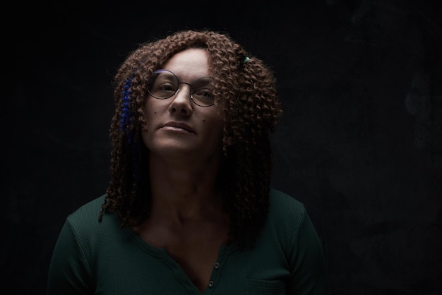 Portret van een authentieke volwassen vrouw met afrokrullen tegen een zwarte muur in de studio. Ongewone stijlvolle vrouw met rood haar