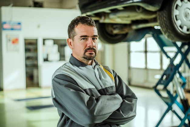 Portret van een autoarbeider van middelbare leeftijd in zijn winkel.