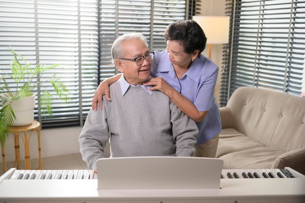 Portret van een Aziatisch bejaarde echtpaar dat thuis piano speelt en geniet