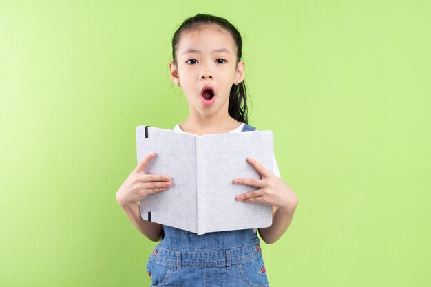 Portret van een Aziatisch kind met een boek op een groene achtergrond