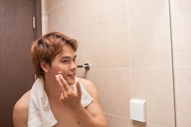 Portret van een Aziatische man die in de badkamer wast