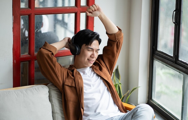 Portret van een Aziatische man die in een café zit met een telefoon en naar muziek luistert