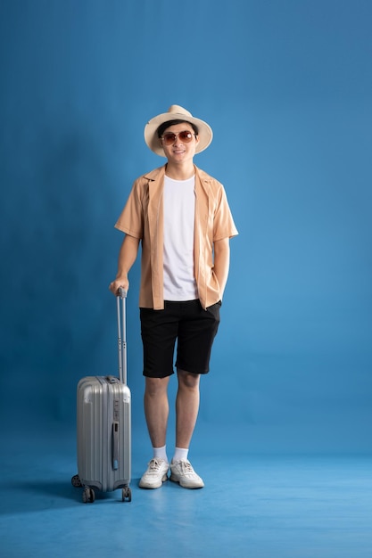 Foto portret van een aziatische man die op een blauwe achtergrond poseert en in de zomer reist