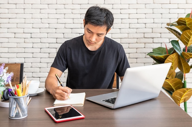 Portret van een Aziatische man freelancer die thuis aan het werk zit aan de eettafel in de woonkamer