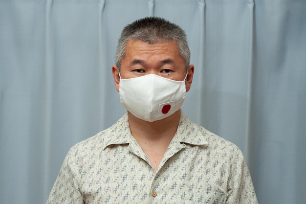 Portret van een aziatische man met een chirurgisch masker met de vlag van japan