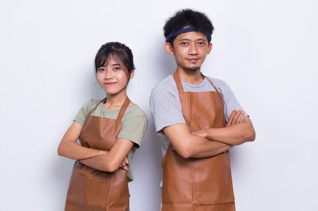 Portret van een Aziatische paar barista-kelner draagt een schort met gekruiste armen geïsoleerd op wit