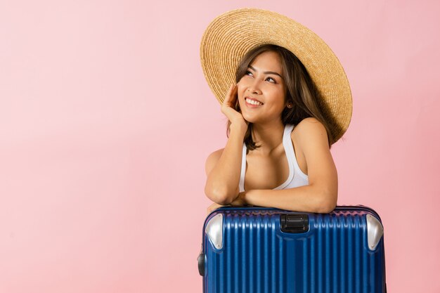 Portret van een Aziatische vrouw die een hoed met brede rand draagt en de zomerkleren die zich met een koffer bevinden.