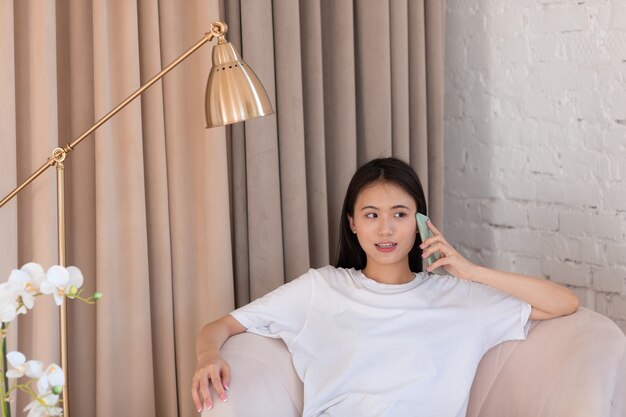 Portret van een Aziatische vrouw die geniet van het gebruik van mobiele telefoons in de woonkamer van het appartement