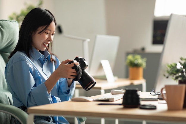 Portret van een Aziatische vrouw met een fotocamera die naar het scherm kijkt