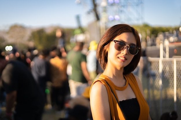 Foto portret van een aziatische vrouw met een zwarte zonnebril die voor het podium staat op het muziekfestival