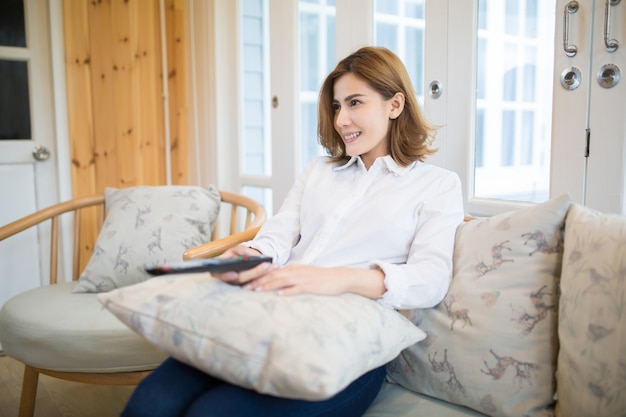 Portret van een Aziatische vrouw om thuis te zitten met de afstandsbediening