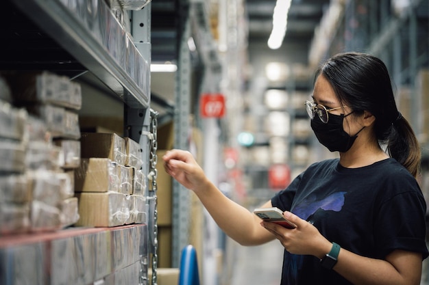 Portret van een aziatische vrouw van een managerarbeider met een masker dat staat en besteldetails op smartphone