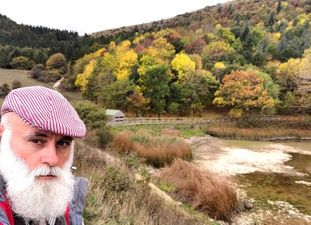 Foto portret van een baarde man tegen bomen in de herfst