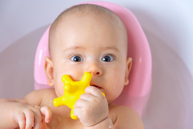 Portret van een baby in een badkamer met een geel speeltje in zijn hand